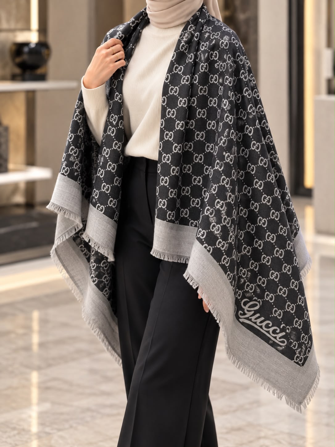 Charcoal black and grey monogram-inspired pashmina wrap with light grey border and fringed edges styled for elegant winter layering.