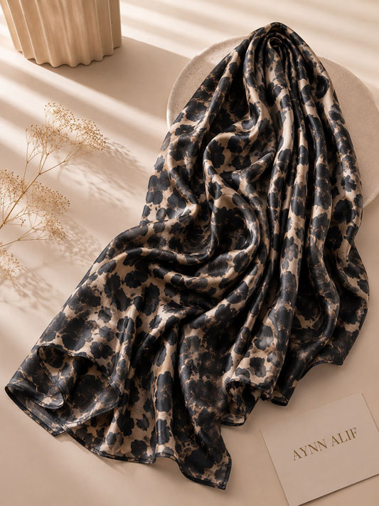 Aynn Alif extra large modal lawn hijab featuring a black and beige leopard print, styled with a soft drape in a neutral aesthetic setting.