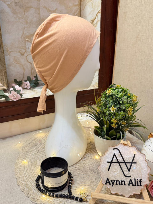 Nude cotton underscarf hijab cap tie back by Aynn Alif displayed on mannequin