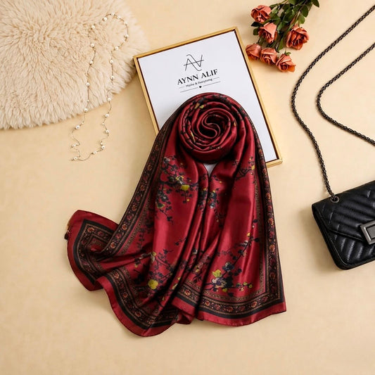 
Rich burgundy printed silk scarf with delicate floral motifs and an elegant patterned border by Aynn Alif