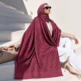 Berry maroon pashmina wrap with tonal geometric pattern, coordinating border and fringed edges styled elegantly over a modest winter outfit.