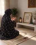 Aynn Alif black namaz chaadar featuring a delicate white mini floral print, styled on a prayer mat in an elegant prayer setting.