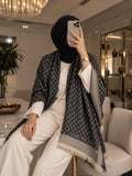 black monogram-inspired pashmina wrap with beige detailing, textured border and fringed edges for elegant winter styling.