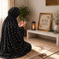 Black namaz chaadar by Aynn Alif featuring tiny mustard-yellow flowers and subtle blue-grey motifs, styled on a prayer mat.