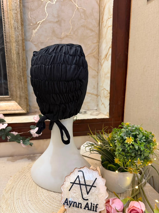 
Black ruched tie back hijab cap made from soft breathable jersey with full head coverage and adjustable tie-back by Aynn Alif.