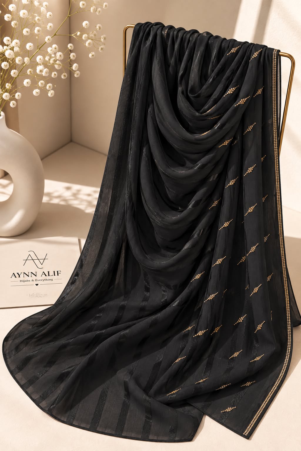 Black crinkle chiffon georgette hijab with satin stripes and delicate stone-studded detailing by Aynn Alif.