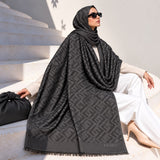 Black pashmina wrap with tonal geometric pattern, coordinating border and fringed edges styled elegantly over a winter outfit.