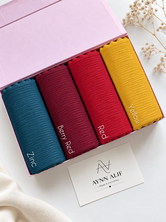 Aynn Alif ribbed jersey hijabs in Zinc, Berry Red, Red and Yellow arranged in a pink box