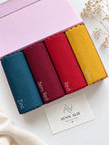 Aynn Alif ribbed jersey hijabs in Zinc, Berry Red, Red and Yellow arranged in a pink box