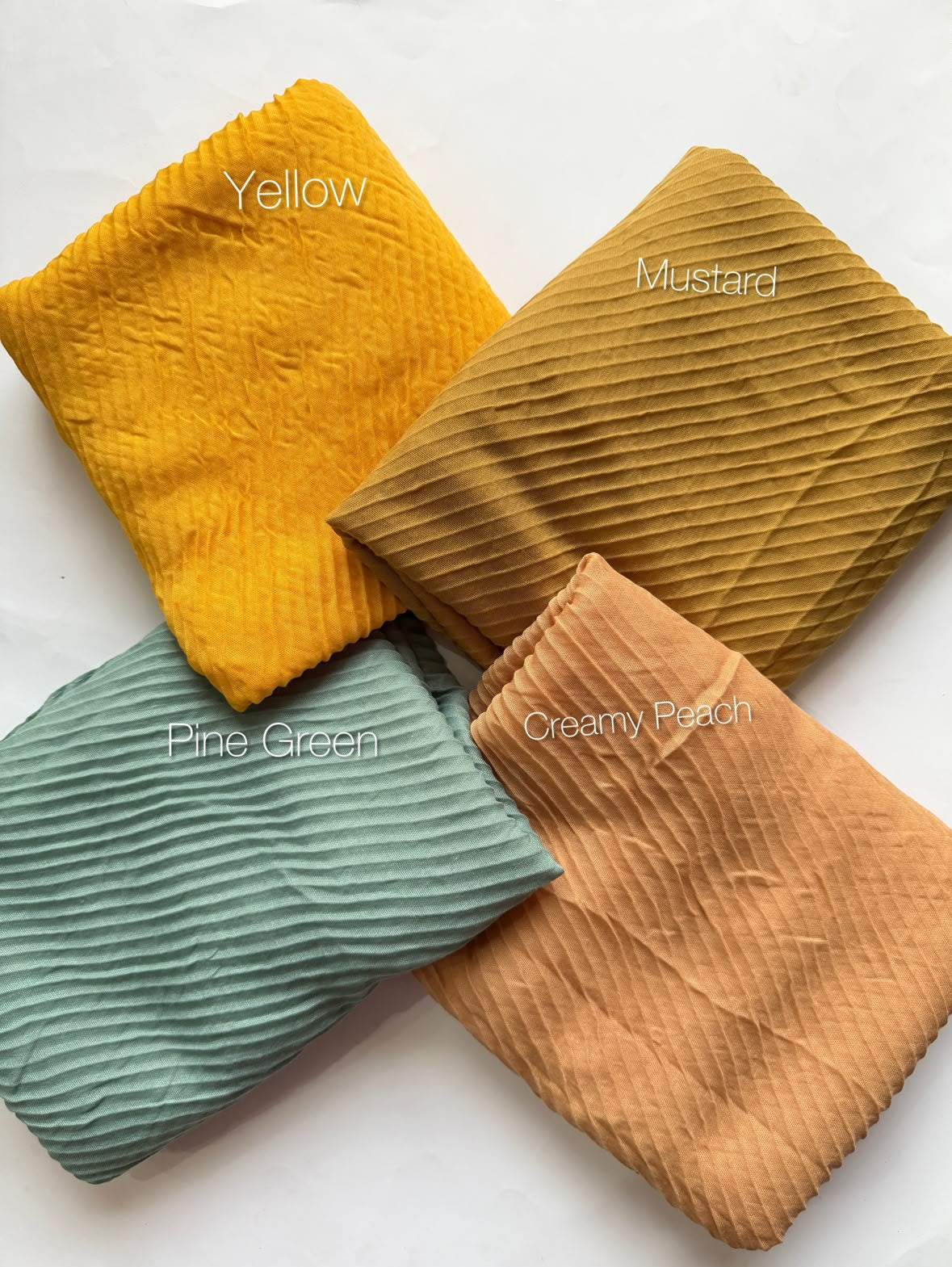 Bubble pleated lawn hijabs by Aynn Alif Pakistan in yellow, mustard, pine green and creamy peach shades with lightweight breathable fabric for everyday modest wear.