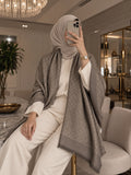 Light brown monogram-inspired pashmina wrap with tonal brown pattern, refined border and fringed edges styled for elegant winter layering.