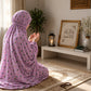 Lilac pink namaz chaadar with a delicate multicolour floral print, styled on a prayer mat in a serene prayer setting by Aynn Alif.