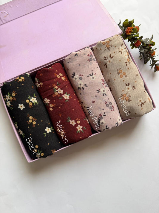 Malaysian printed lawn hijabs in Black, Maroon, Tea Pink and Khaki stacked in a display box. Lightweight breathable fabric for everyday styling.