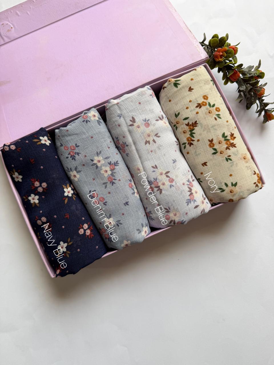 Malaysian printed lawn hijabs in Navy Blue, Denim Blue, Powder Blue and Ivory stacked in a display box. Soft breathable lawn fabric for daily wear.