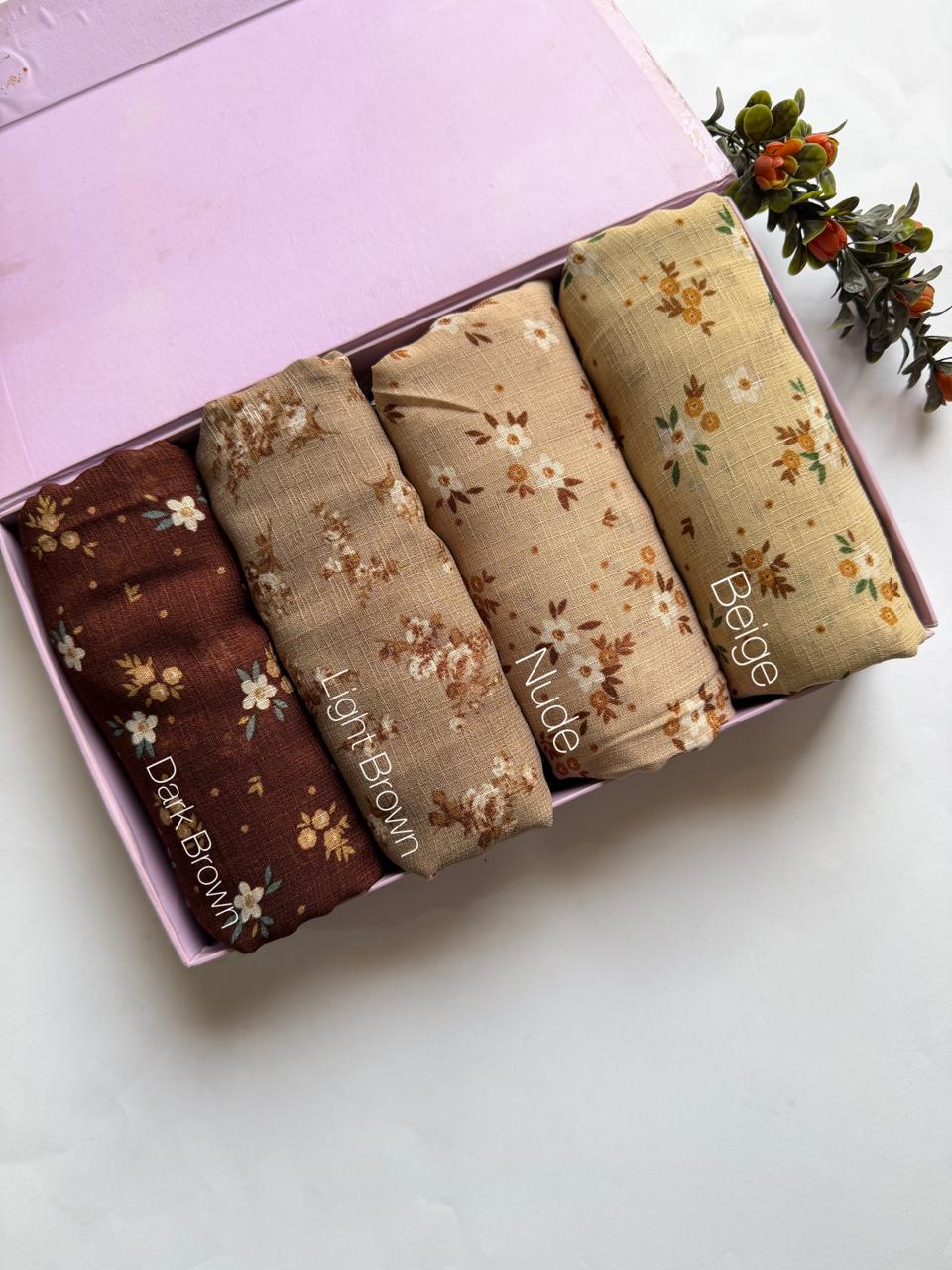 Malaysian printed lawn hijabs in Dark Brown, Light Brown, Nude and Beige stacked in a display box. Soft breathable lawn fabric for daily wear.