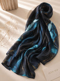Aynn Alif extra large printed modal lawn hijab featuring a black base with aqua blue marble design and gold accents, styled in a luxury flat lay.