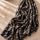 
Aynn Alif extra large modal lawn hijab featuring a black and beige leopard print, styled with a soft drape in a neutral aesthetic setting.