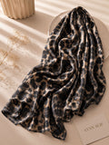 
Aynn Alif extra large modal lawn hijab featuring a black and beige leopard print, styled with a soft drape in a neutral aesthetic setting.