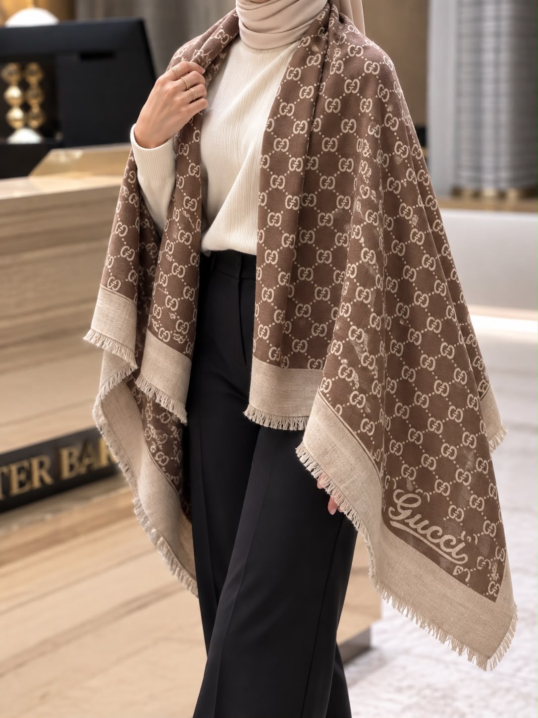Mocha brown monogram-inspired pashmina wrap with cream detailing, wide beige border and fringed edges styled for elegant winter layering.