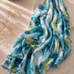 Extra large modal lawn hijab featuring an abstract watercolor print in aqua blue, teal, ivory and soft lime tones, styled in an elegant draped flatlay.