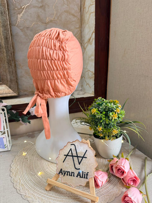 Orangish Peach ruched tie back hijab cap made from soft breathable jersey with full head coverage and adjustable tie-back by Aynn Alif.