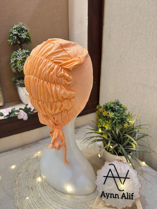 Peach ruched tie back hijab cap made from soft breathable jersey with full head coverage and adjustable tie-back by Aynn Alif.
