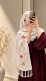 Pearl white cashmere embroidered hijab featuring pink and green floral motifs, delicate sequin embellishments, and matching white fringed edges by Aynn Alif.