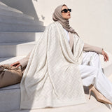 Pearl White pashmina wrap with subtle tonal geometric pattern and fringed edges, styled elegantly over a modest winter outfit.
