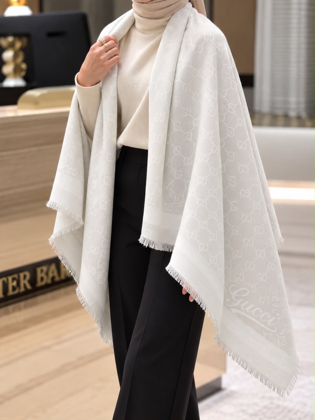 Pearl white monogram-inspired pashmina wrap with subtle tonal pattern, coordinating border and delicate fringed edges for elegant winter styling.