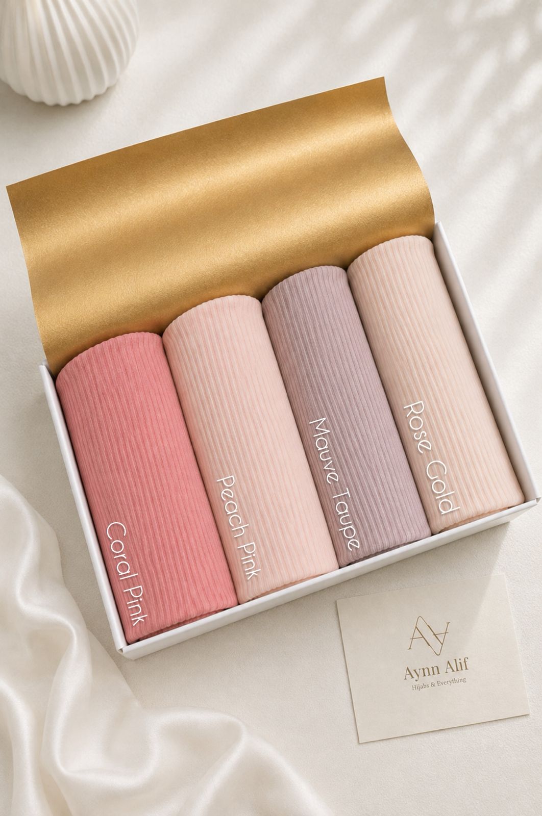Aynn Alif large ribbed jersey hijabs in Coral Pink, Peach Pink, Mauve Taupe and Rose Gold arranged in a white presentation box.