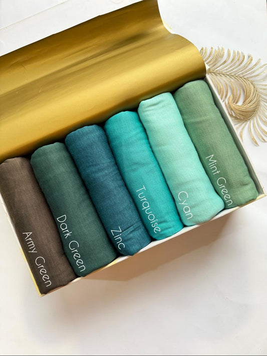 Plain jersey hijabs in shades of green displayed in minimal aesthetic setup