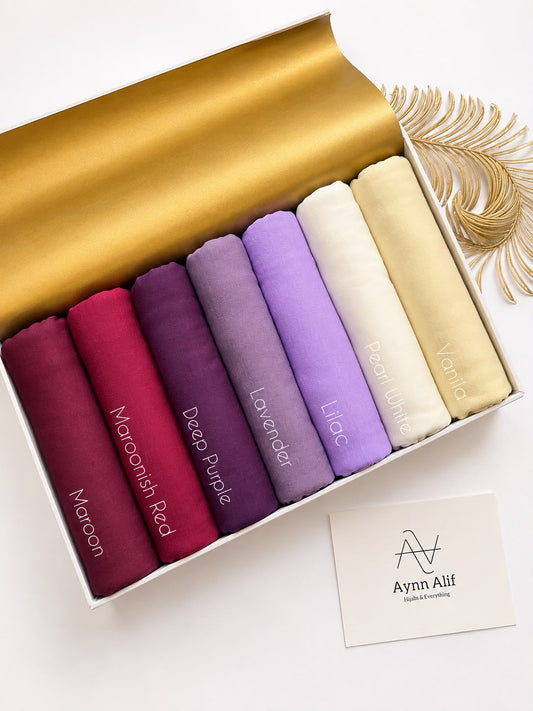 Plain jersey hijabs in maroon, red and purple shades arranged neatly in a box. 