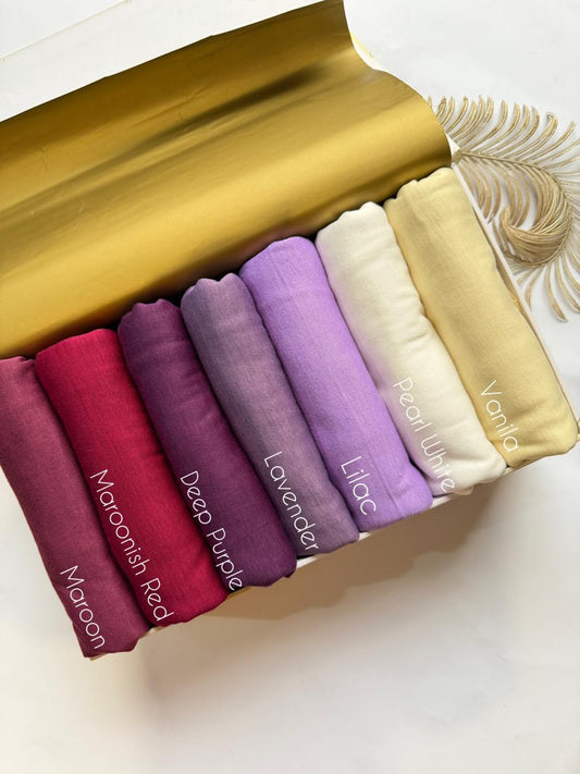 Plain jersey hijabs in maroon, red and purple shades arranged neatly in a box. 