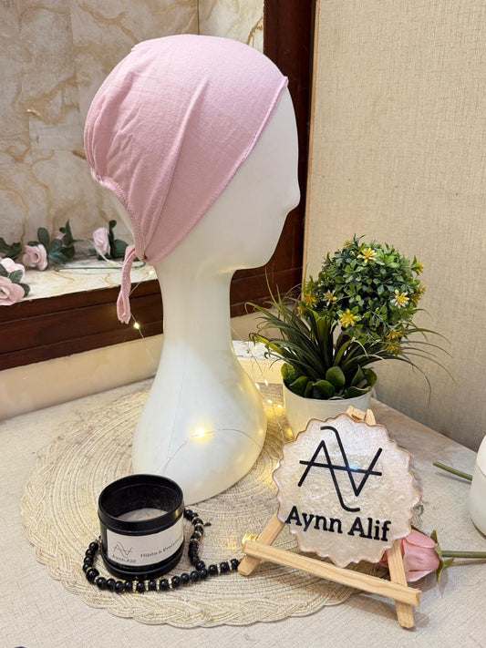Powder pink plain tie-back hijab cap in breathable stretch fabric on mannequin for modest wear