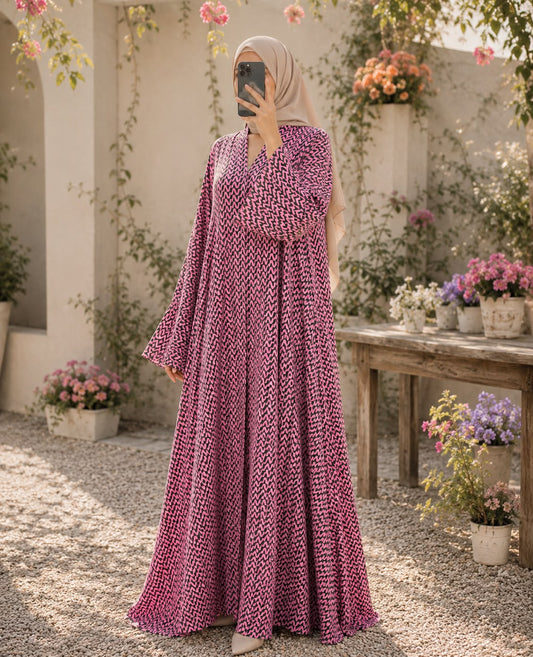 Pink printed front open abaya in Korean Nidah with a double-flare silhouette, styled with a neutral hijab in a flower-filled courtyard.