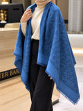 Royal blue monogram-inspired pashmina wrap with tonal blue pattern, coordinating border and fringed edges styled for elegant winter layering