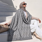 Silver grey geometric pashmina wrap with contrasting interlocking pattern, coordinating border and fringed edges styled for an elegant winter look.