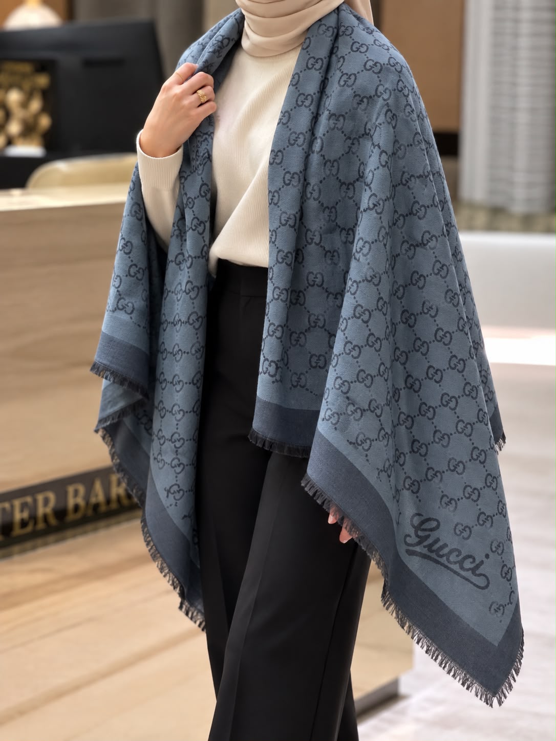 Slate blue monogram-inspired pashmina wrap with dark grey detailing, wide border and fringed edges styled for elegant winter layering