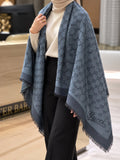 Slate blue monogram-inspired pashmina wrap with dark grey detailing, wide border and fringed edges styled for elegant winter layering
