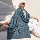 Steel blue geometric monogram-inspired pashmina wrap with tonal blue-grey pattern, coordinating border and fringed edges for elegant winter styling.