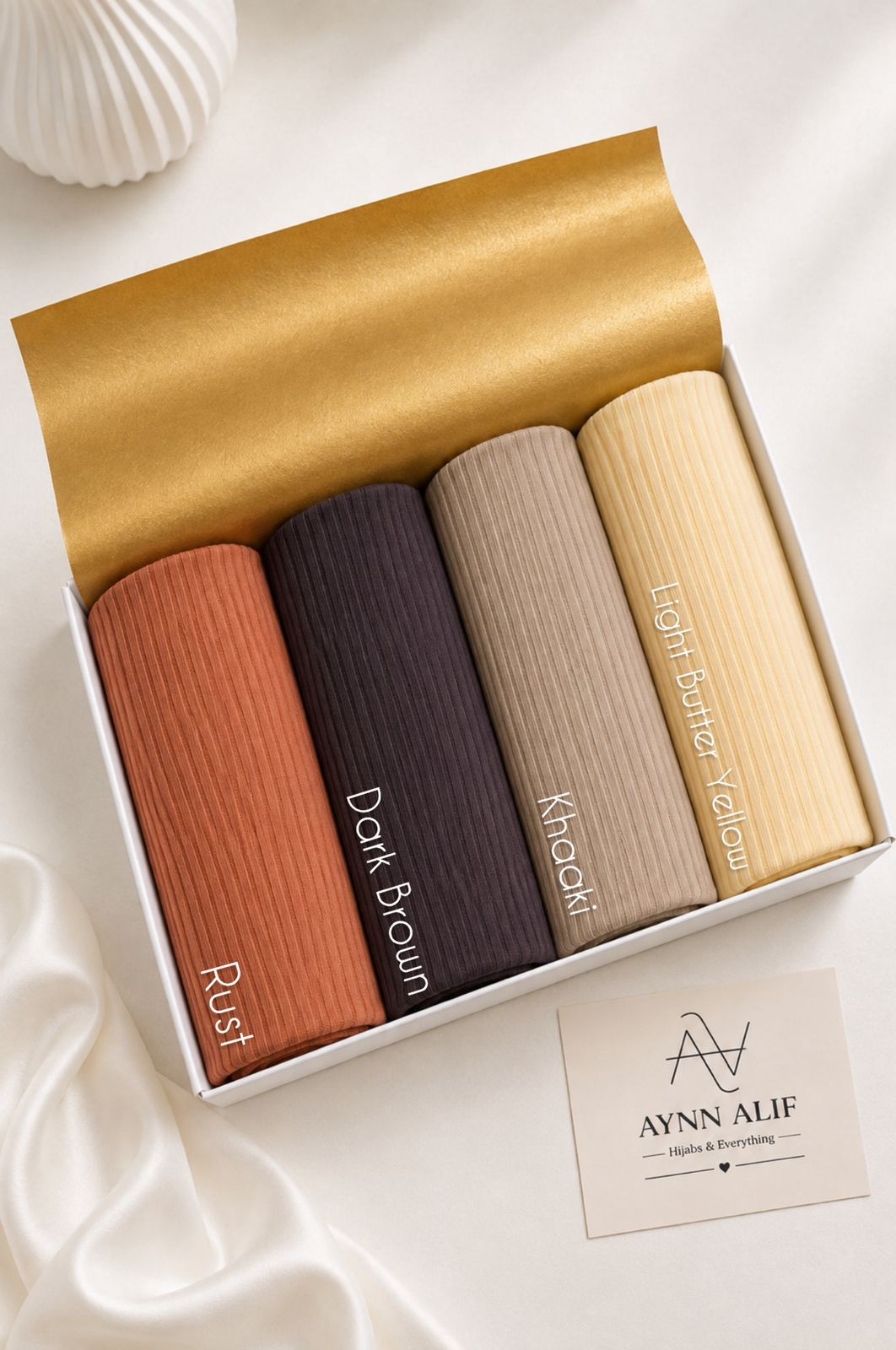 Aynn Alif large ribbed jersey hijabs in Rust, Dark Brown, Khaaki and Light Butter Yellow, arranged in a white presentation box.